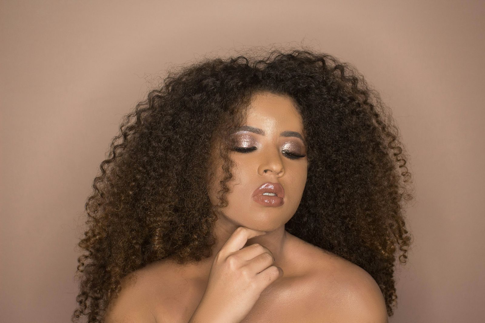 A woman with a full head of dark brown curls and shimmering bronze eye make-up