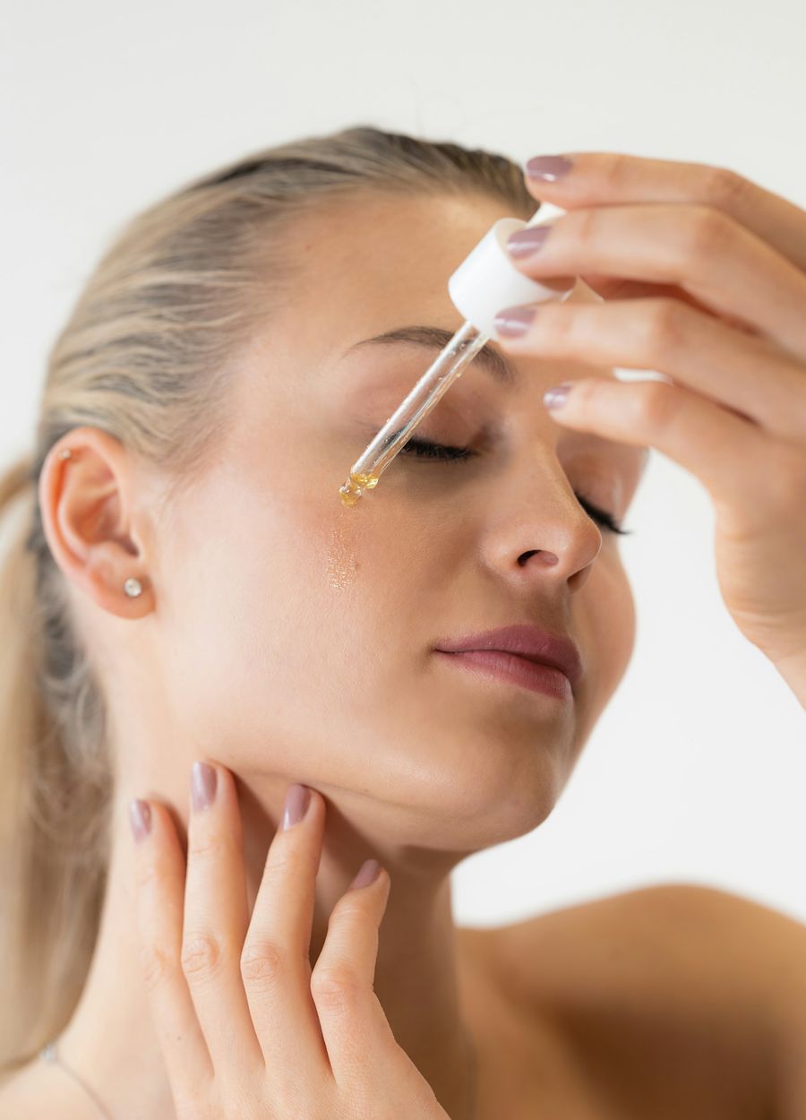 A woman with her eyes closed smoothing a drop of serum onto her forehead